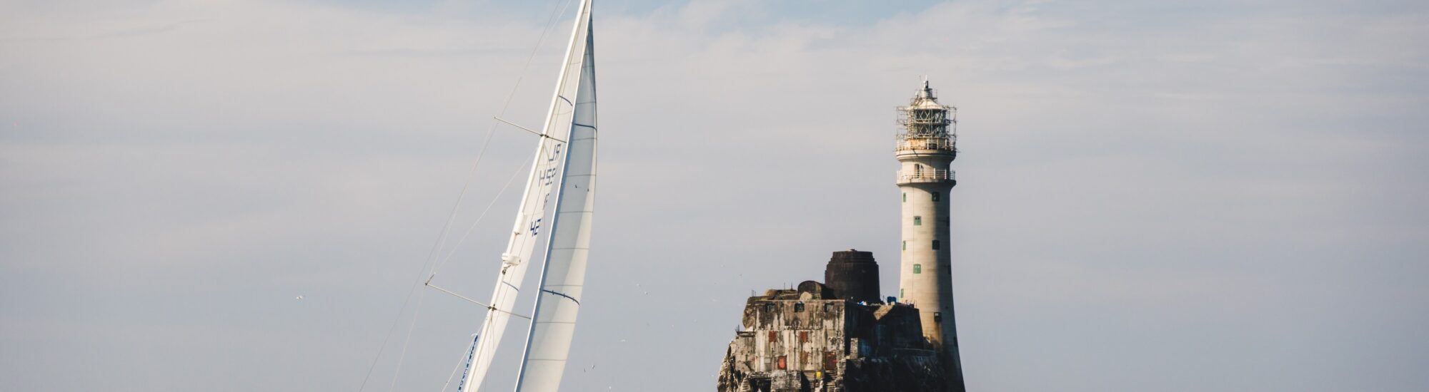 Un voilier aux abord du phare de Fastnet rock - © timursalikhov 