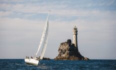 Un voilier aux abord du phare de Fastnet rock - © timursalikhov