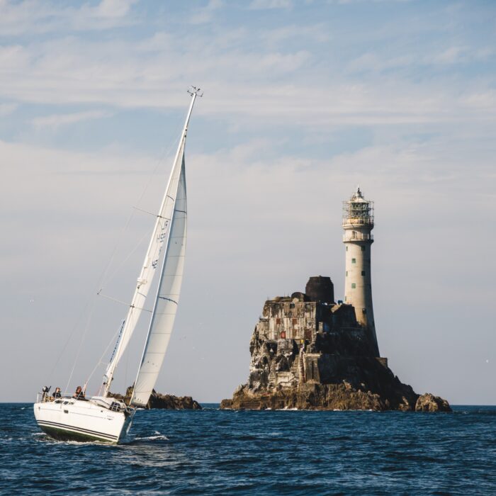 Un voilier aux abord du phare de Fastnet rock - © timursalikhov