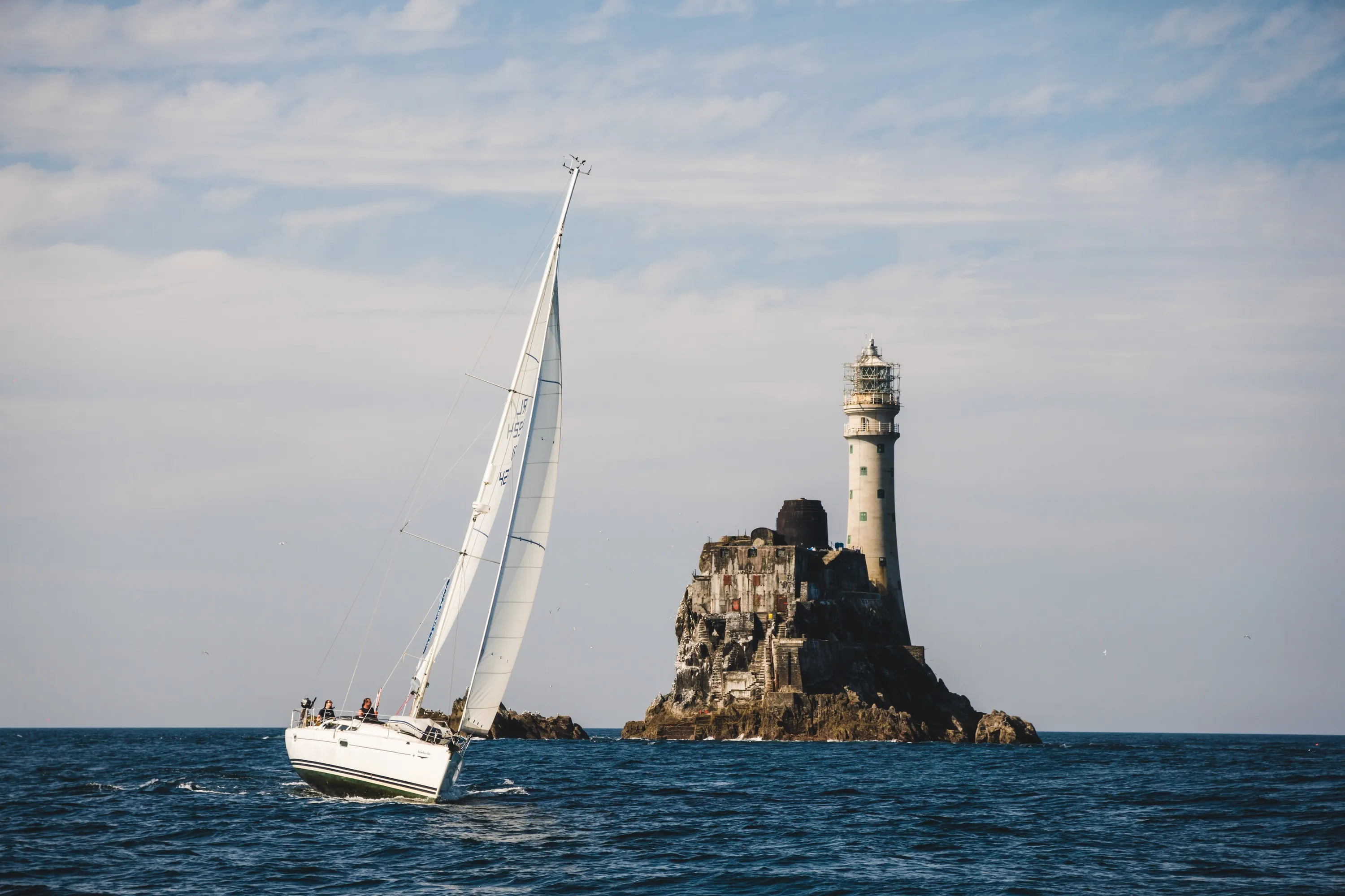 Un voilier aux abord du phare de Fastnet rock - © timursalikhov