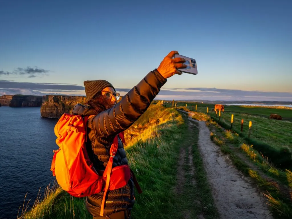 Une voyageuse prenant un selfie face aux Falaises de Moher - © Tolo