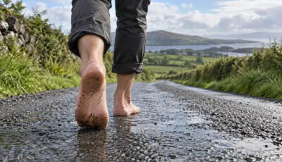 Pieds nus d’un marcheur sur une route humide dans la campagne irlandaise