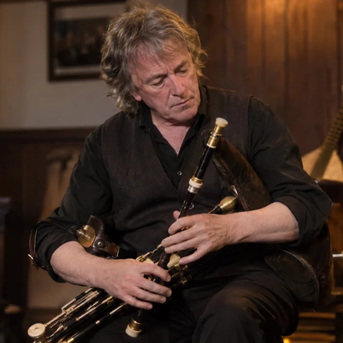 Portrait de Paddy Keenan jouant des uilleann pipes dans une salle de musique irlandaise