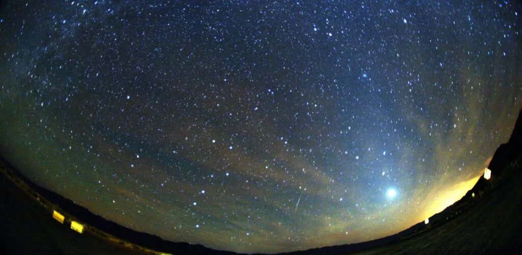 Trace lumineuse verte et rouge d’un météore des Orionides dans un ciel étoilé.